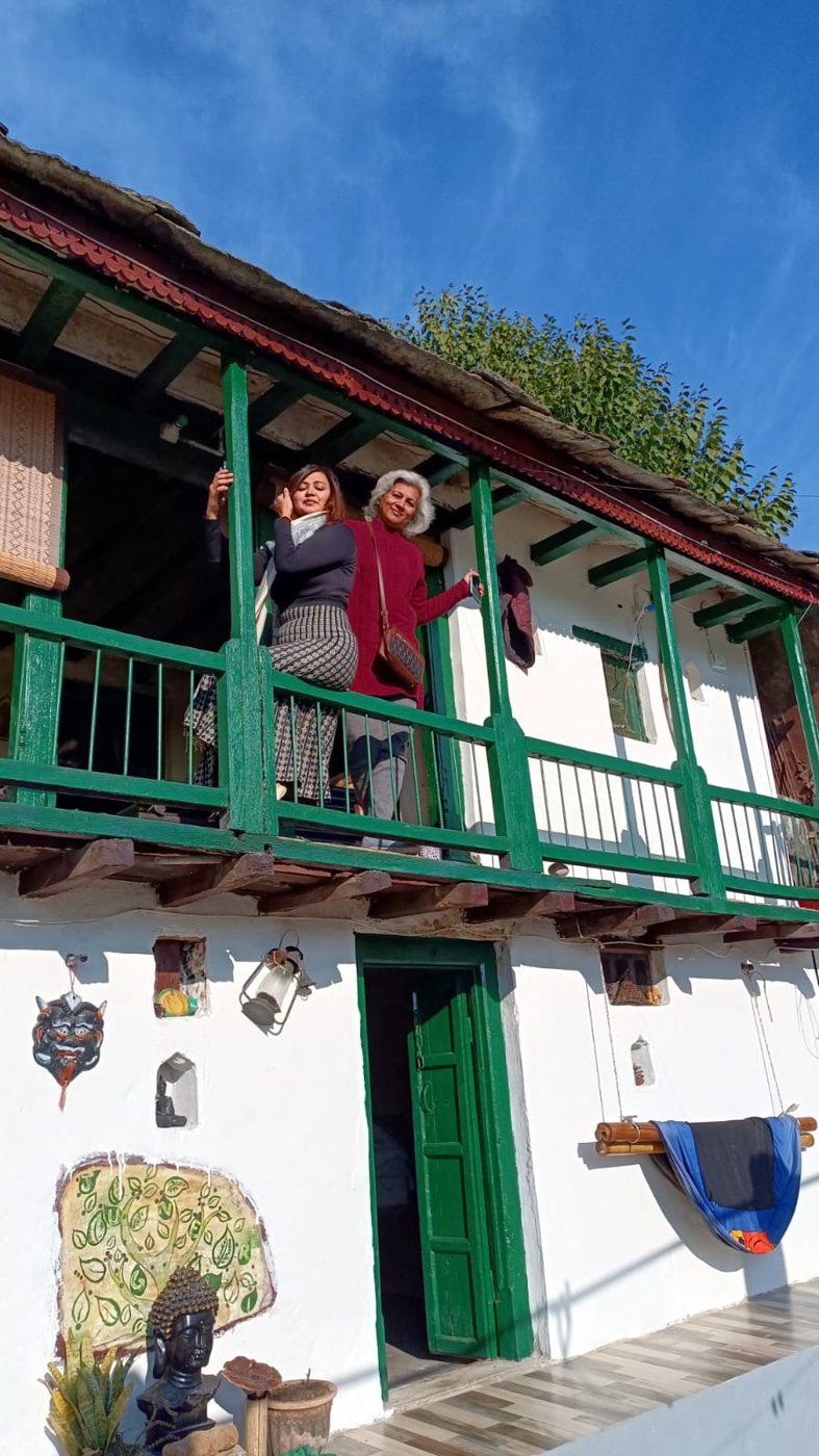 The traditional Garhwali farmhouse at Junegiri, with its green carved-timber balcony, under a blue sky