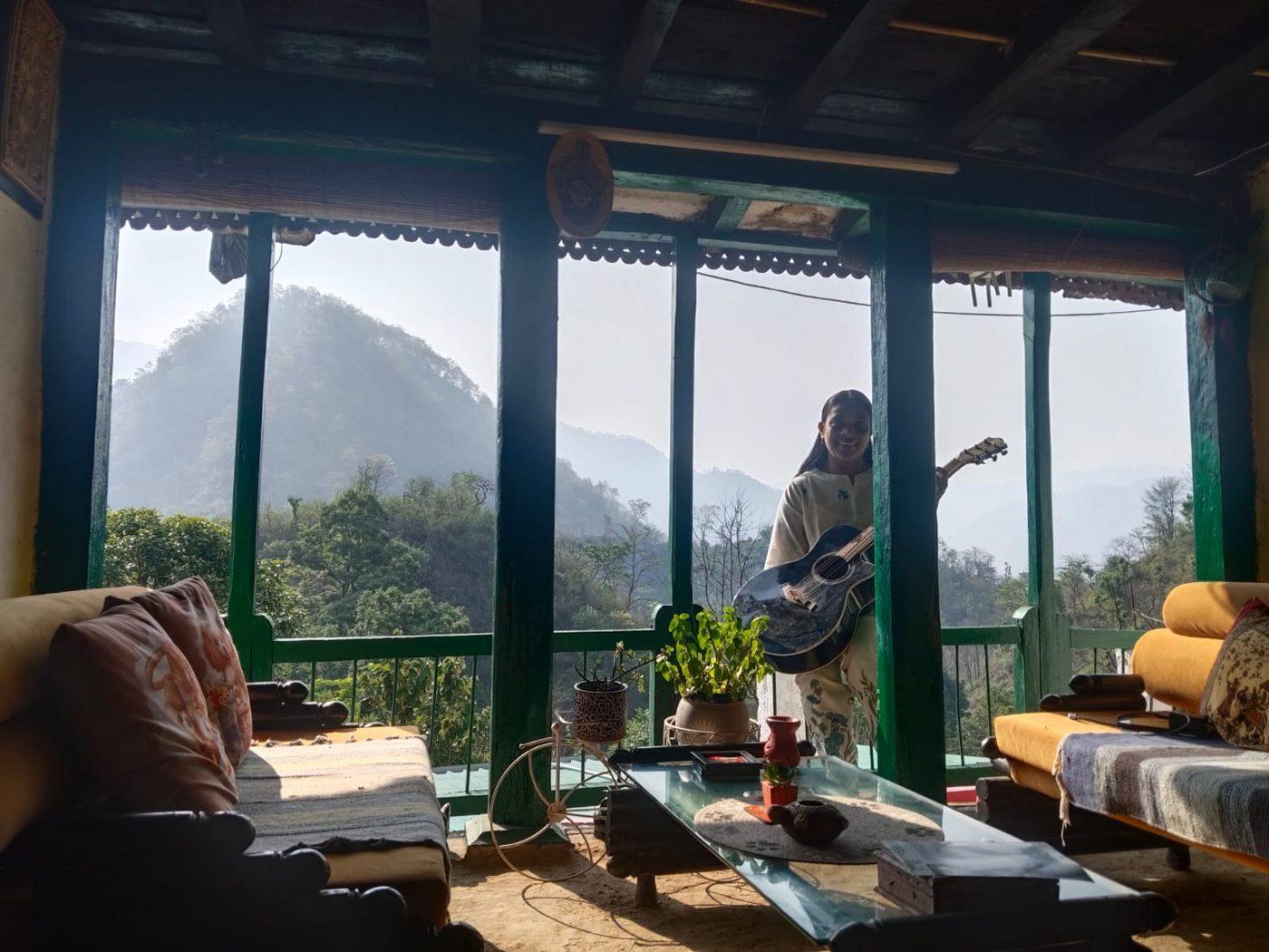 The open veranda common room, looking out through green timber posts to the hills beyond