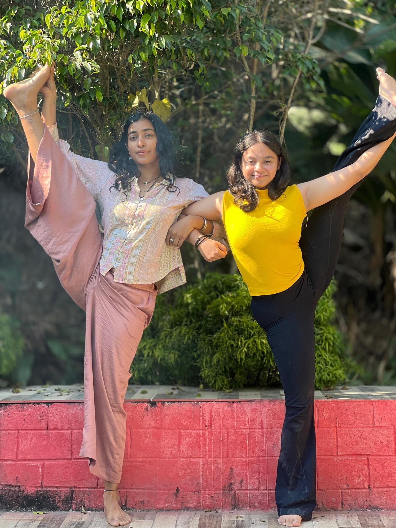 Two students balancing side by side in extended hand-to-big-toe pose in the garden
